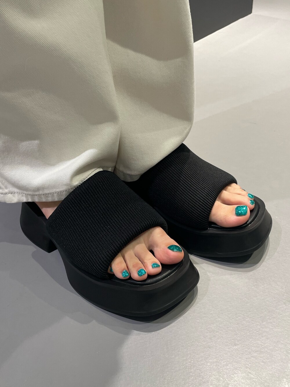 ブラック系のTシャツ/カットソー、グレー系のデニムスカート、ブラック系のサンダルを着用したレディースの夏コーディネートの8枚目の写真