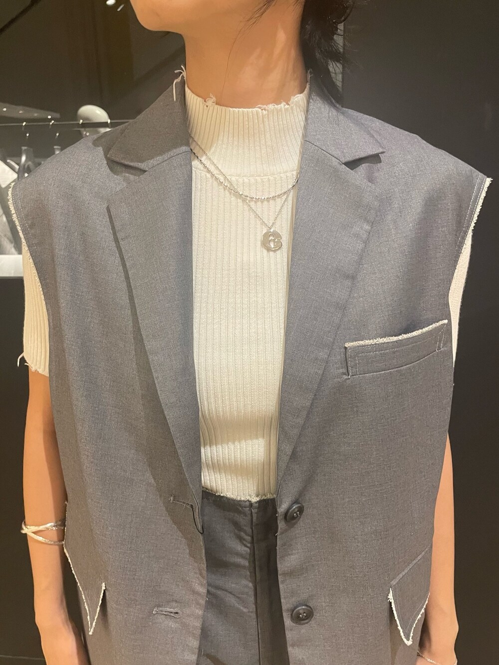 ホワイト系のニット/セーター、ホワイト系のハンドバッグ、グレー系のベストを着用したレディースの夏コーディネートの4枚目の写真