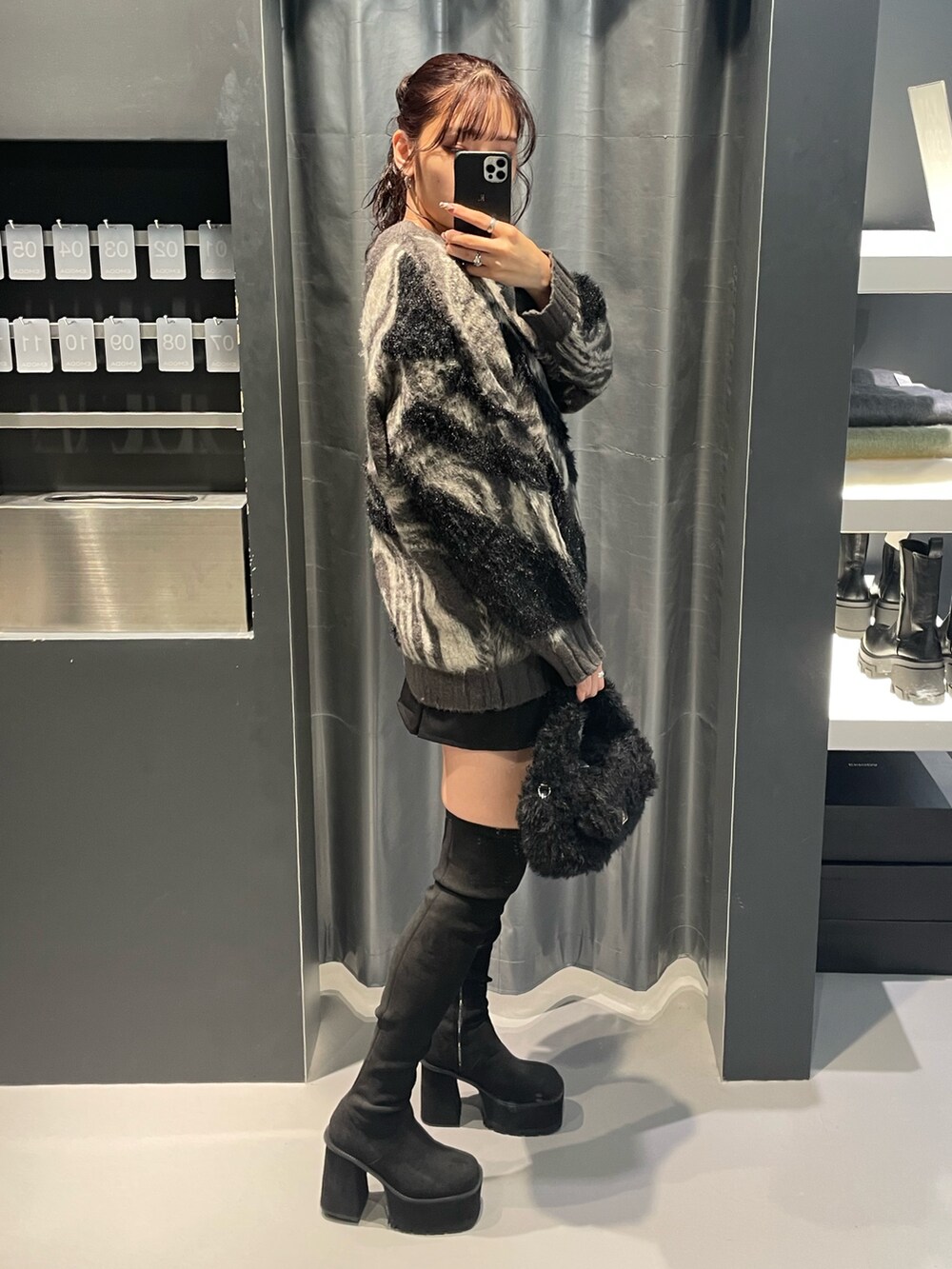 グレー系のニット/セーター、ブラック系のスカート、ブラック系のハンドバッグを着用したレディースの冬コーディネートの2枚目の写真