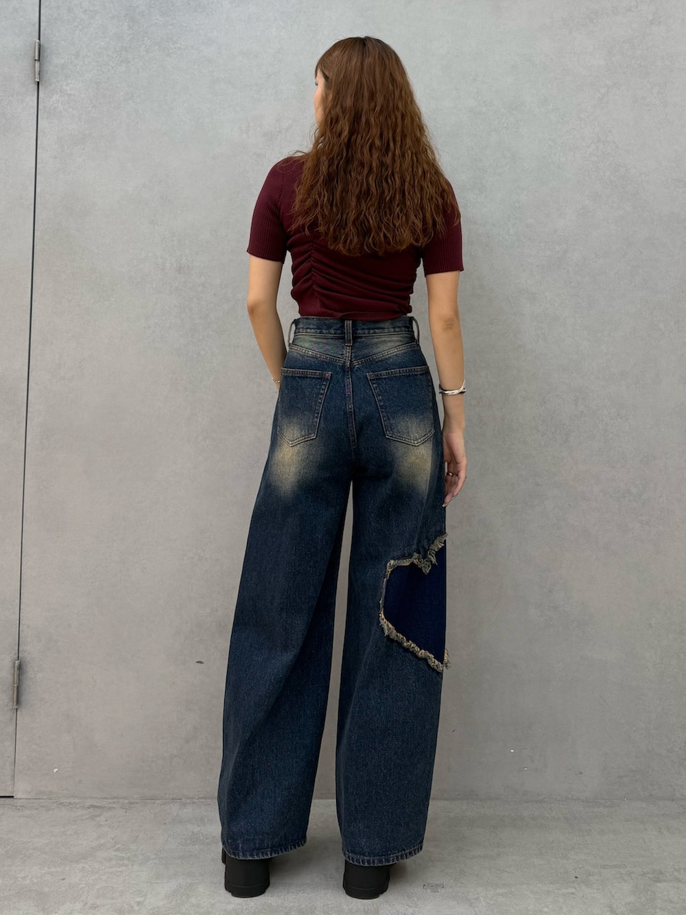 レッド系のニット/セーター、ブルー系のデニムパンツ、ブラック系のブーツを着用したレディースの夏コーディネートの3枚目の写真
