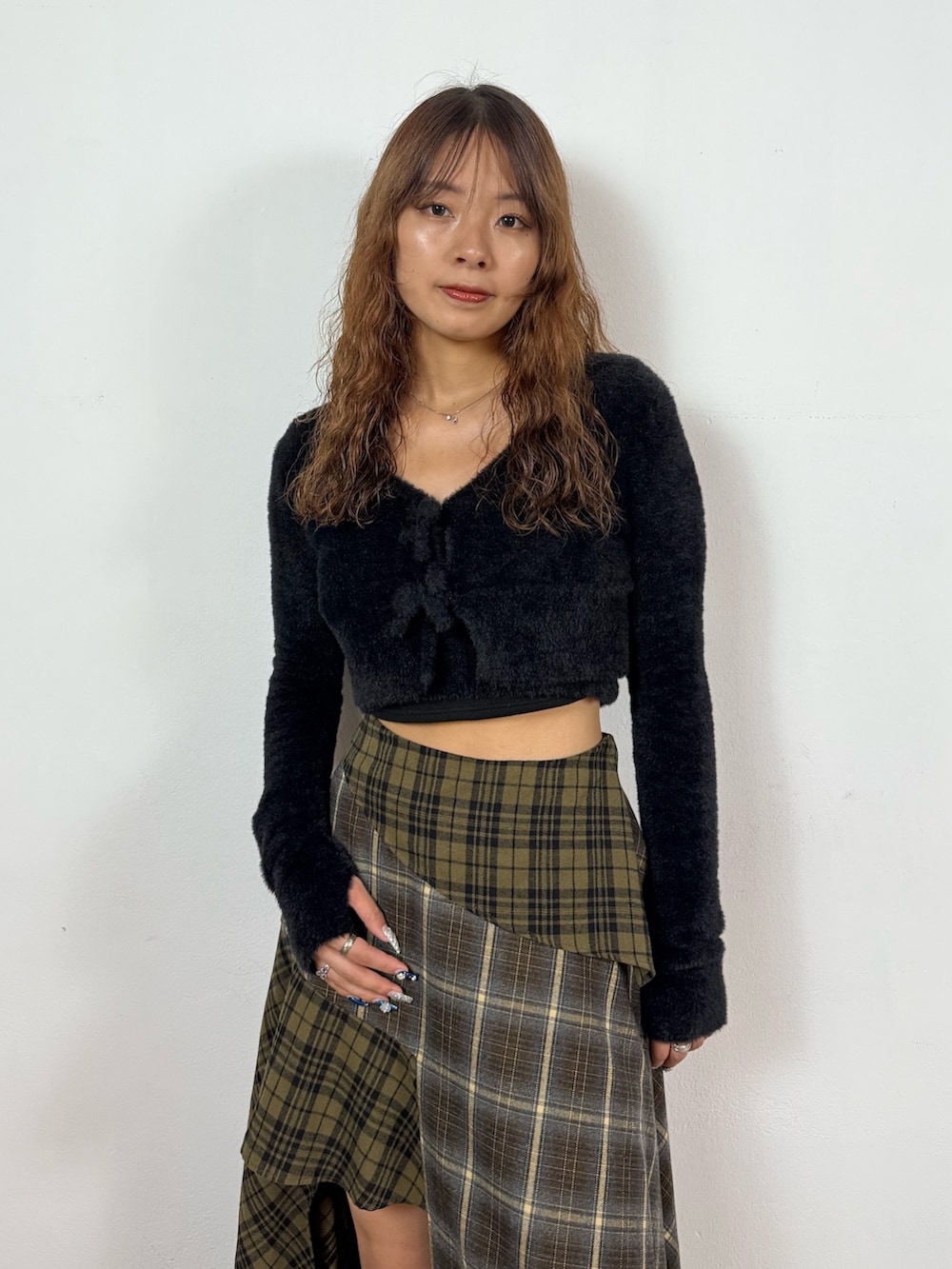 ブラック系のニット/セーター、グリーン系のスカート、ブラック系のブーツを着用したレディースの秋コーディネートの4枚目の写真