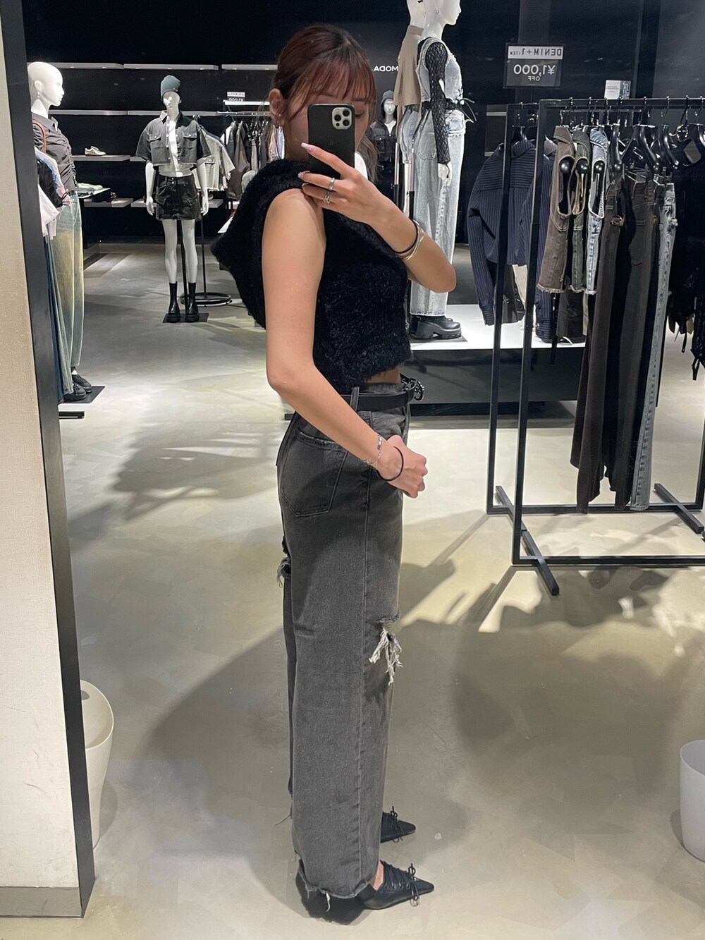 ブラック系のニット/セーター、ブラック系のデニムパンツ、ブラック系のパンプスを着用したレディースの春コーディネートの2枚目の写真