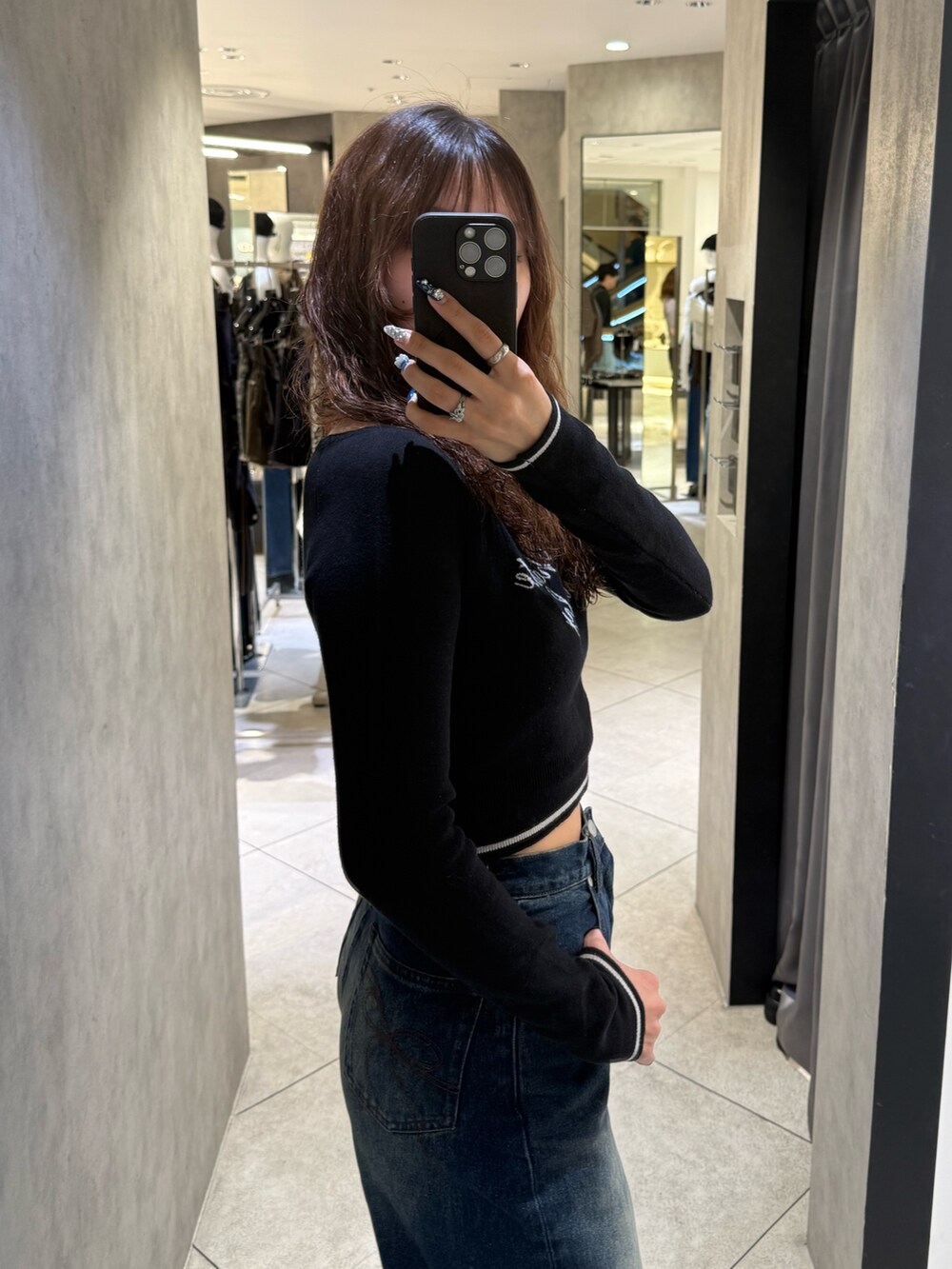 ブラック系のブーツ、ブラック系のニット/セーター、ブルー系のデニムパンツを着用したレディースの秋コーディネートの5枚目の写真