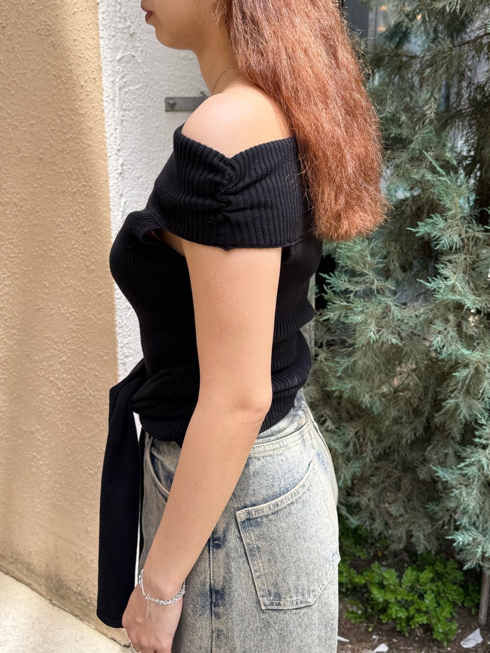 ブラック系のニット/セーター、ブルー系のデニムパンツ、ブラック系のサンダルを着用したレディースの夏コーディネートの5枚目の写真