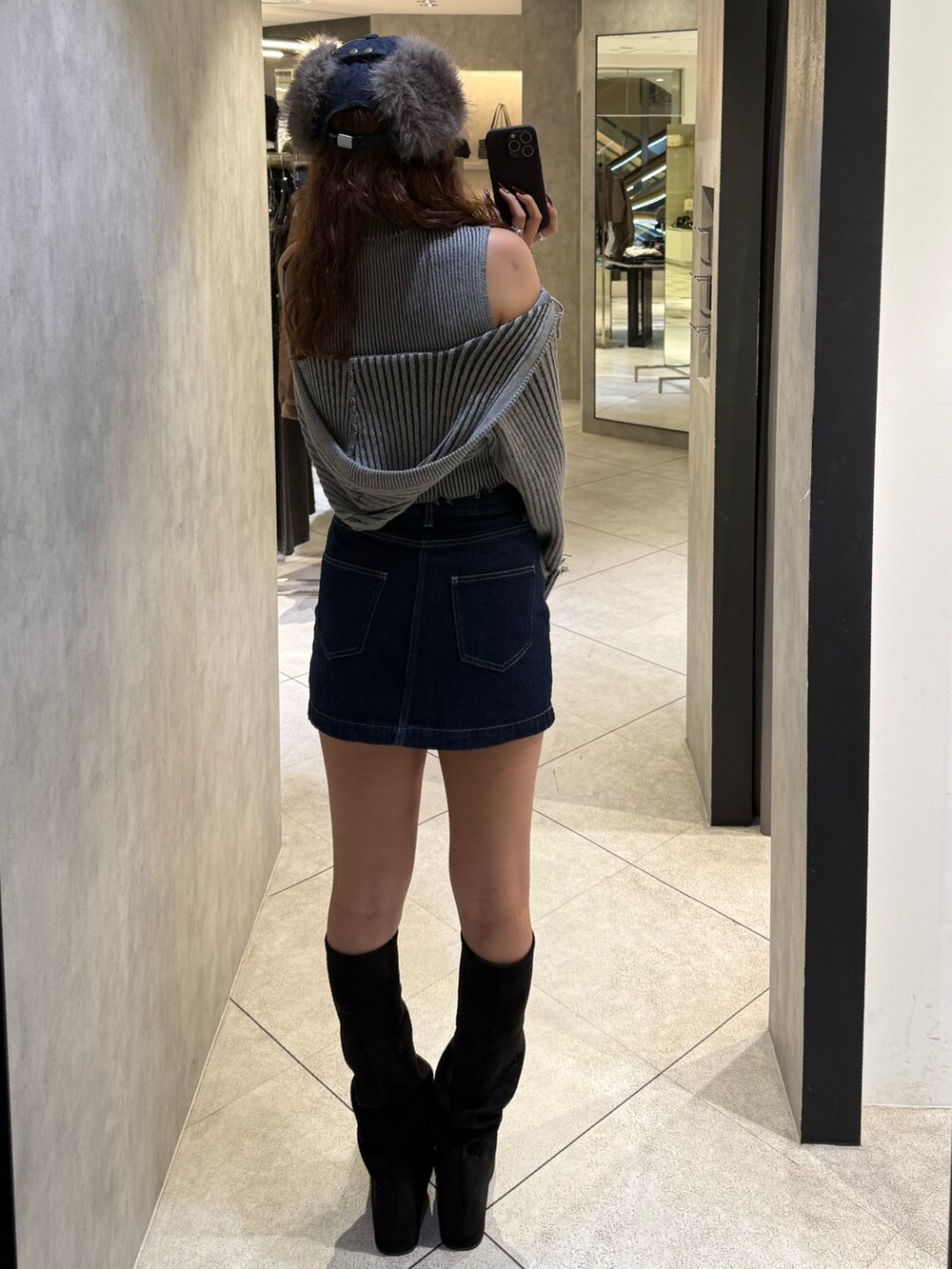 グレー系のニット/セーター、ブルー系のスカート、ブラック系のブーツを着用したレディースの秋コーディネートの3枚目の写真