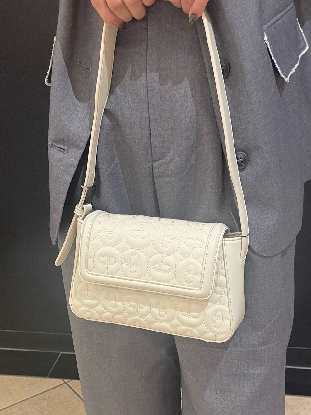 ホワイト系のニット/セーター、ホワイト系のハンドバッグ、グレー系のベストを着用したレディースの夏コーディネートの7枚目の写真