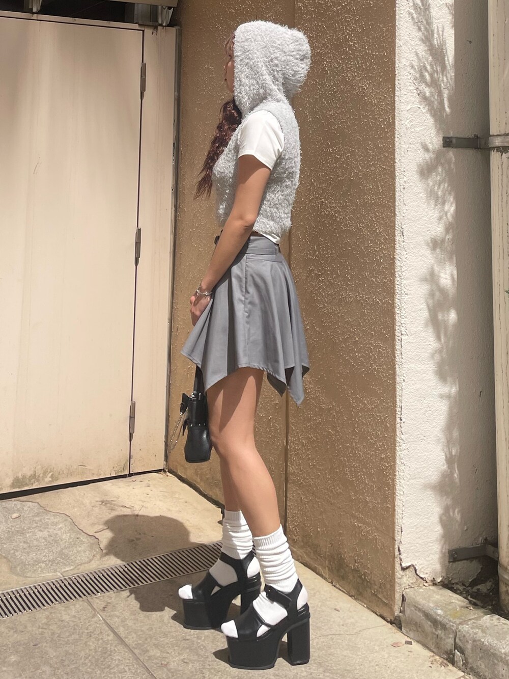 ホワイト系のTシャツ/カットソー、グレー系のニット/セーター、グレー系のスカートを着用したレディースの春コーディネートの2枚目の写真