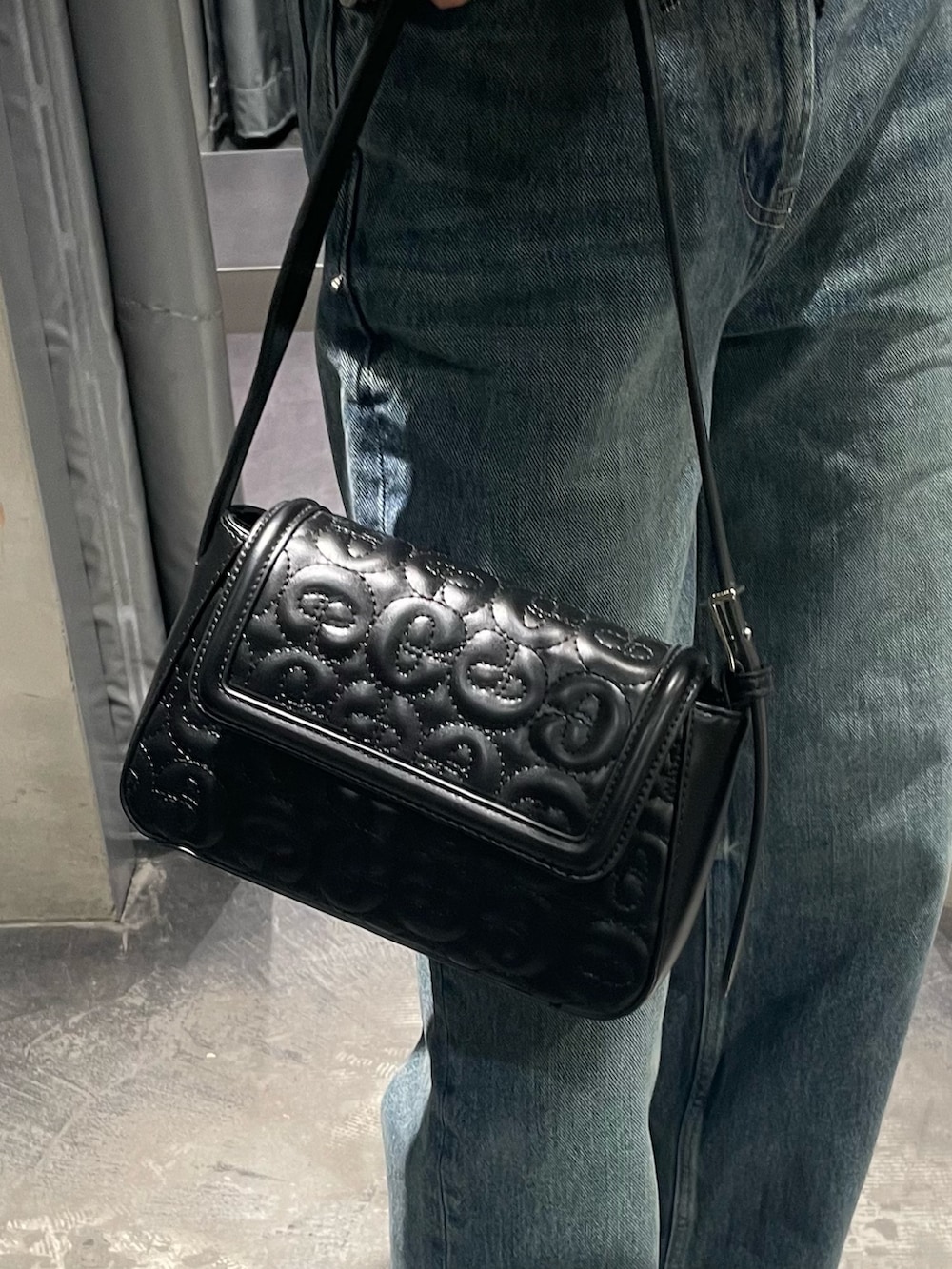 ブルー系のデニムパンツ、ブラック系のブーツ、ブラック系のハンドバッグを着用したレディースの秋コーディネートの6枚目の写真