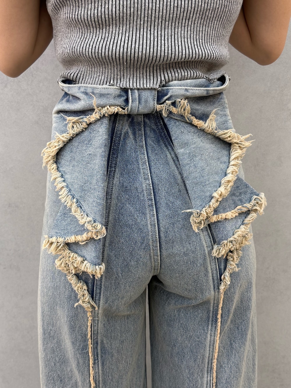 ブラック系のニット/セーター、ブルー系のデニムパンツ、ブラック系のサンダルを着用したレディースの春コーディネートの4枚目の写真