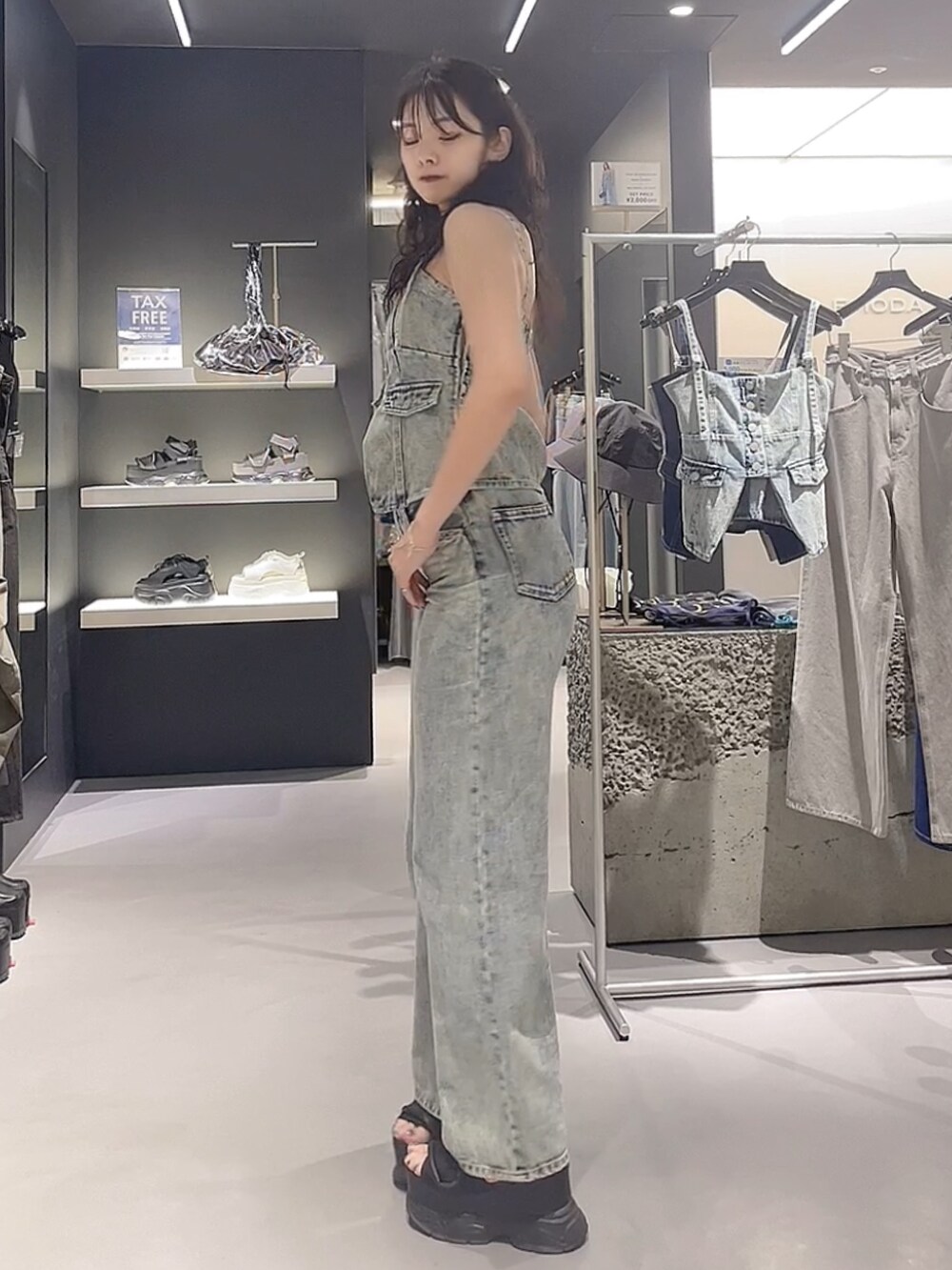 ブルー系のキャミソール、ブルー系のデニムパンツ、ブラック系のサンダルを着用したレディースの夏コーディネートの2枚目の写真