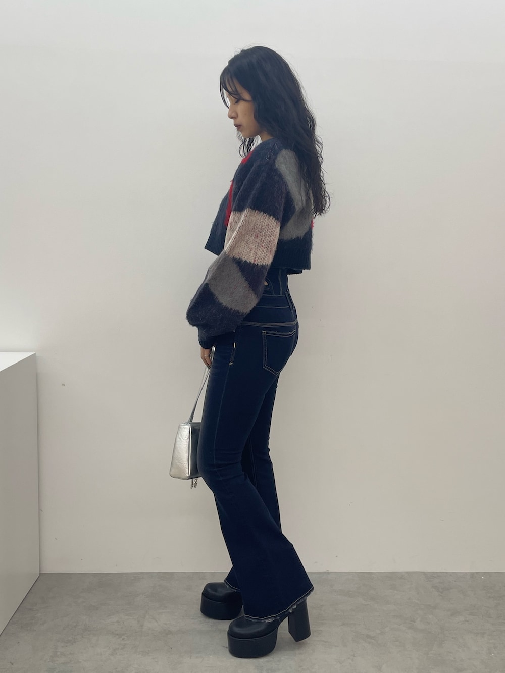 ブルー系のニット/セーター、ブルー系のデニムパンツ、ブラック系のブーツを着用したレディースの夏コーディネートの2枚目の写真