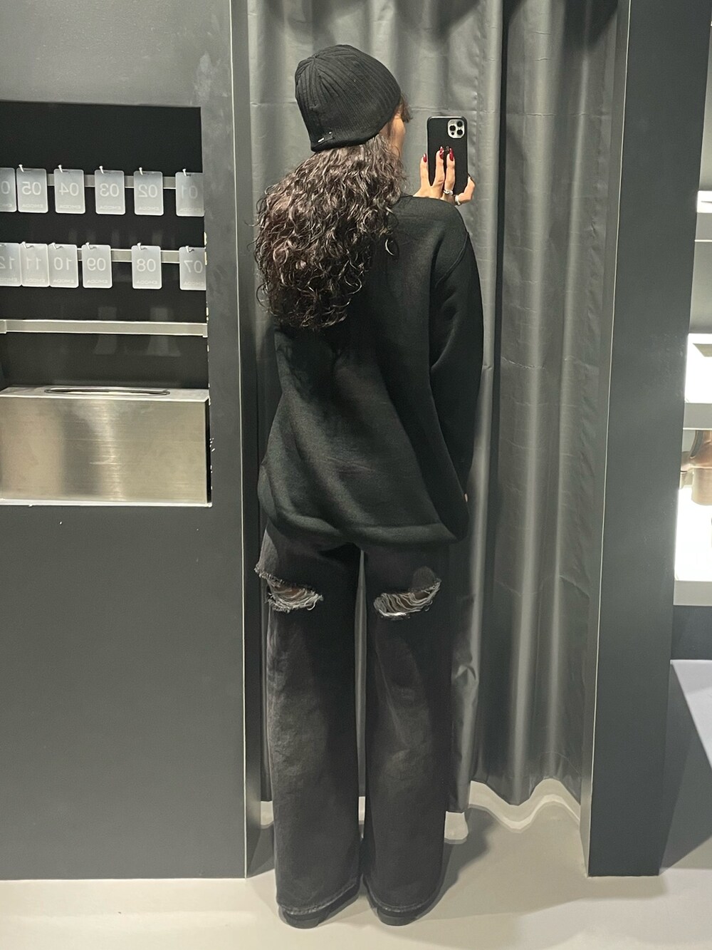 ブラック系のワンピース、ブラック系のデニムパンツ、ブラック系のブーツを着用したレディースの秋コーディネートの3枚目の写真