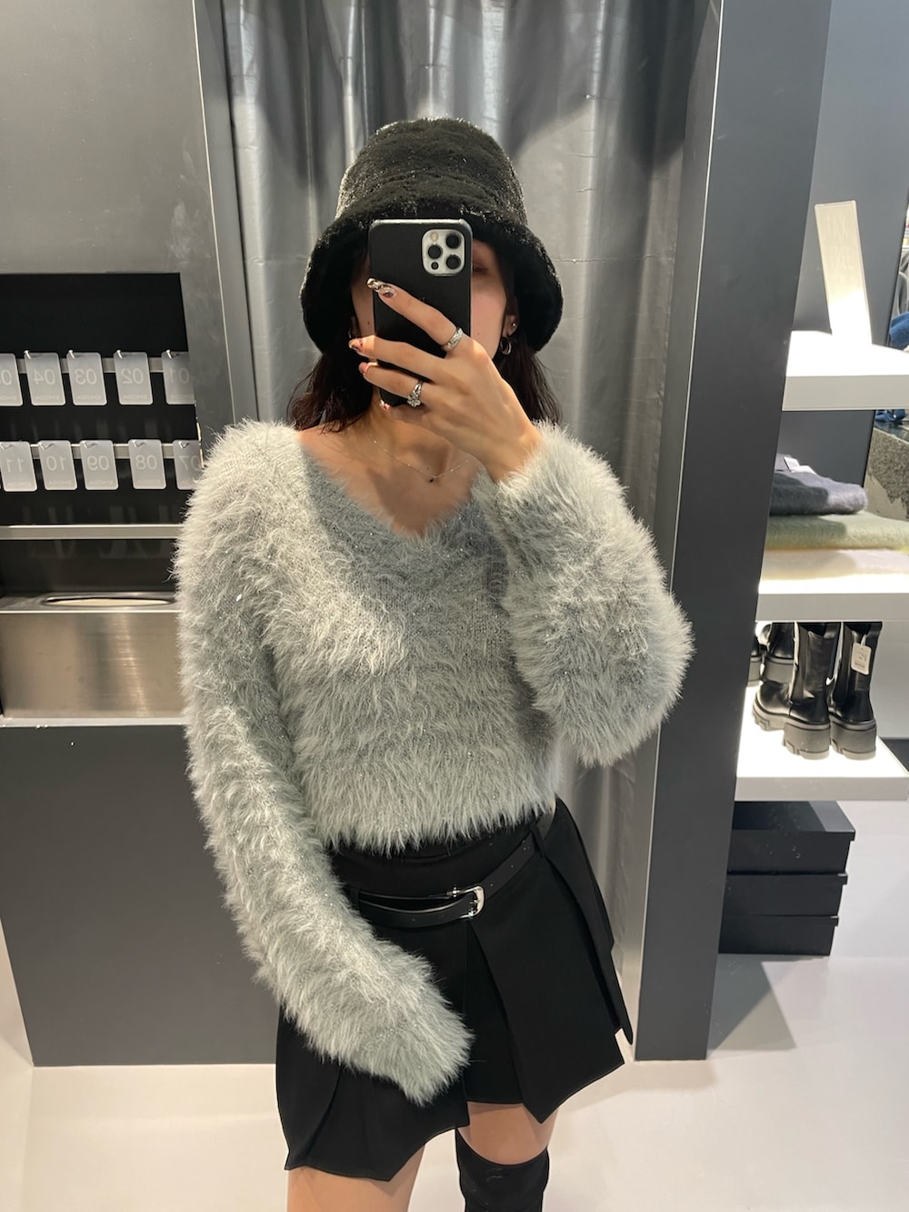 グレー系のニット/セーター、ブラック系のスカート、ブラック系のブーツを着用したレディースの秋コーディネートの4枚目の写真