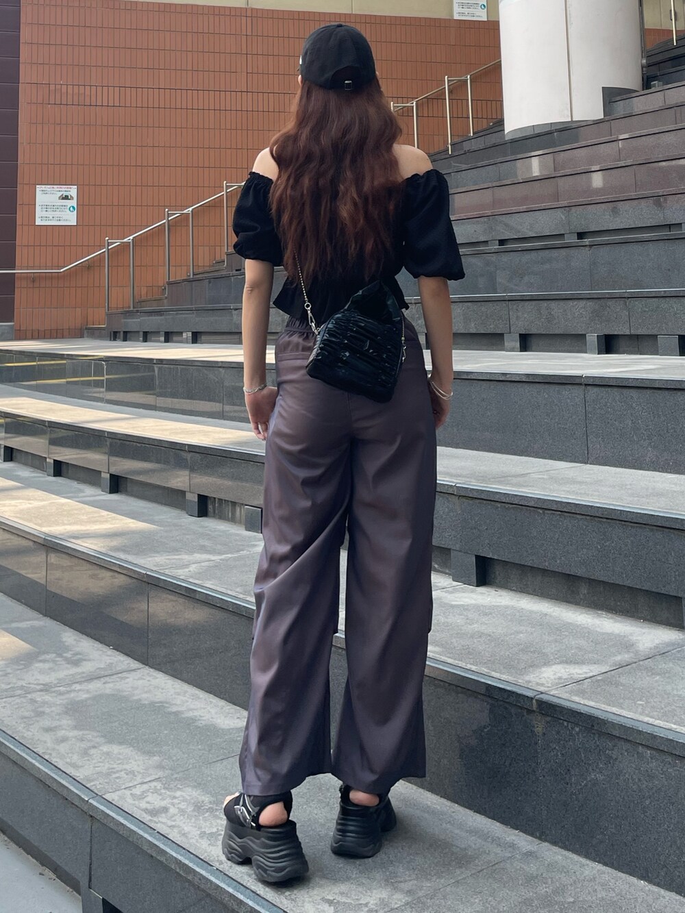 ブラック系のハンドバッグ、ブラック系のTシャツ/カットソー、ブラウン系のその他パンツを着用したレディースの春コーディネートの3枚目の写真