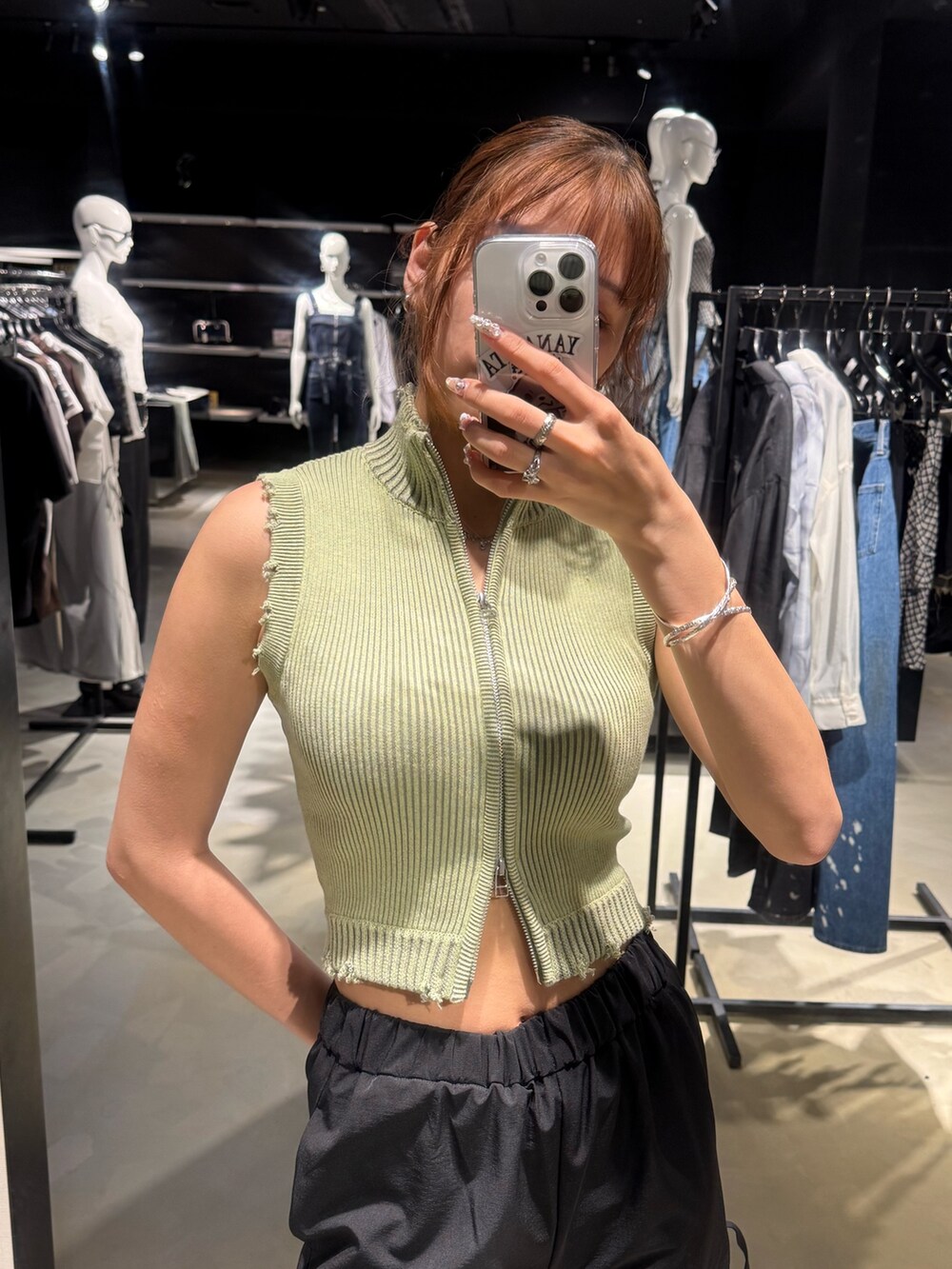 グリーン系のタンクトップ、ブルー系のデニムパンツ、ブラック系のハンドバッグを着用したレディースの夏コーディネートの4枚目の写真