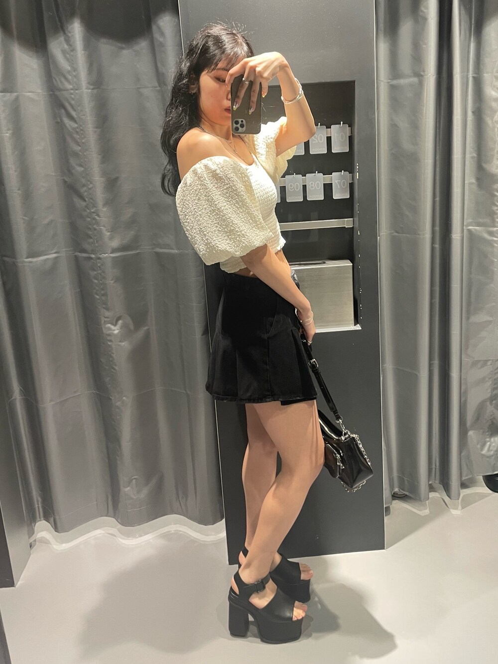 ホワイト系のTシャツ/カットソー、ブラック系のデニムスカート、ブラック系のショルダーバッグを着用したレディースの春コーディネートの2枚目の写真