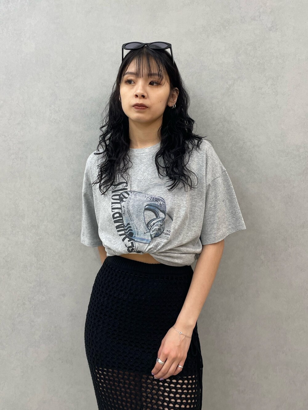 グレー系のTシャツ/カットソー、ブラック系のスカート、ブラック系のサンダルを着用したレディースの春コーディネートの4枚目の写真