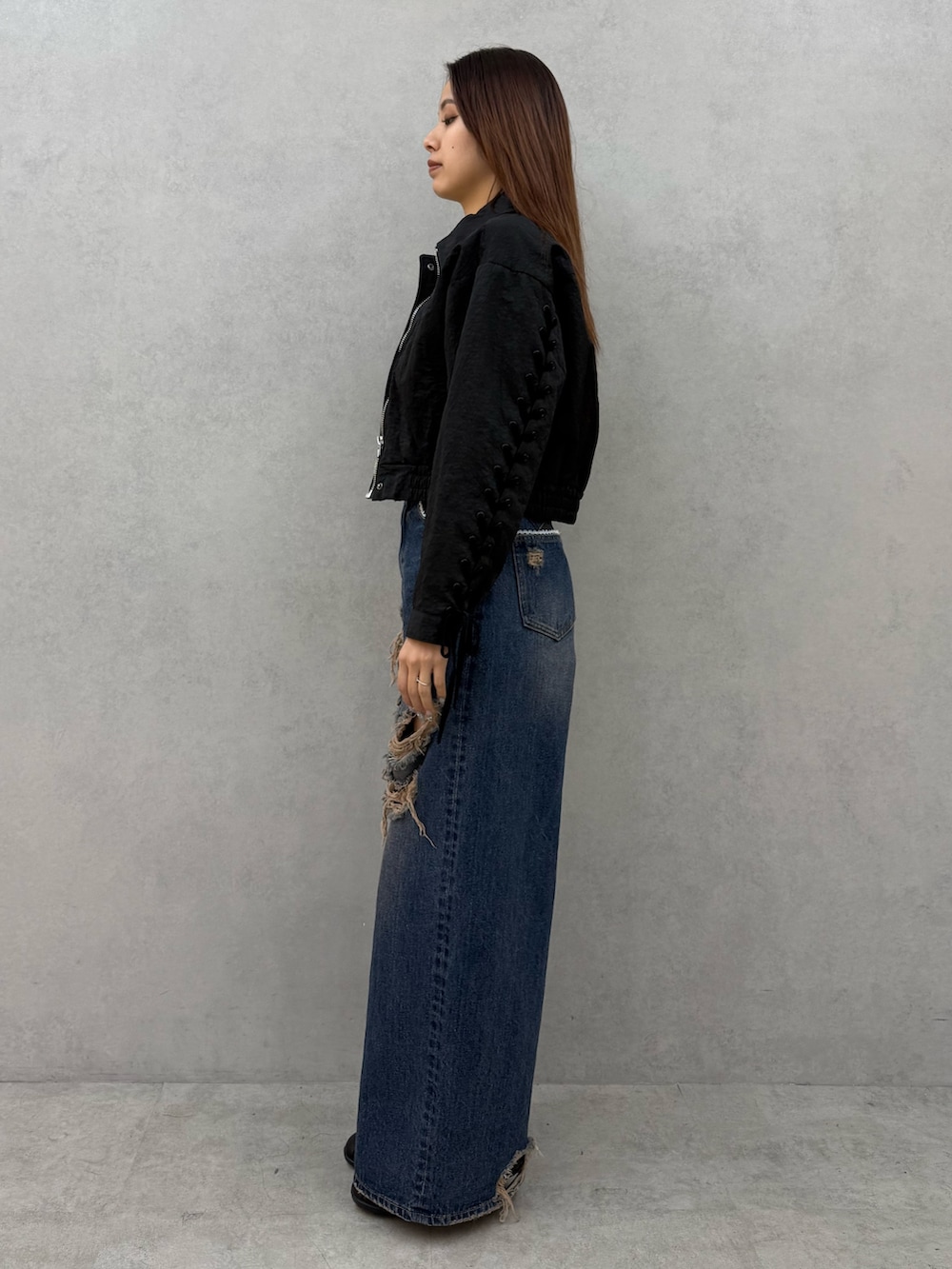 ブラック系のブルゾン、ホワイト系のニット/セーター、ブルー系のデニムパンツを着用したレディースの冬コーディネートの2枚目の写真