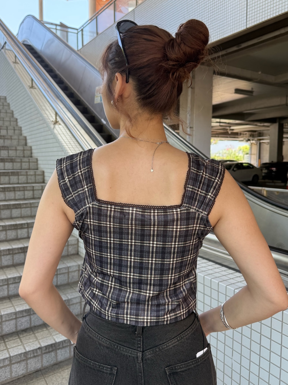 ブラウン系のタンクトップ、ブラック系のハンドバッグ、ブラック系のデニムパンツを着用したレディースの夏コーディネートの6枚目の写真