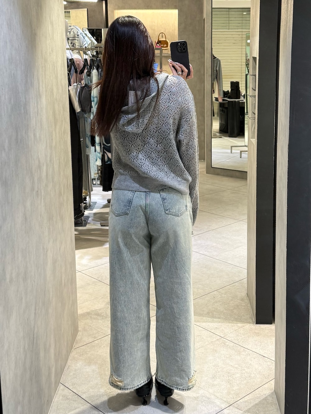 ブラック系のスニーカー、ブルー系のデニムパンツ、グレー系のパーカーを着用したレディースの春コーディネートの3枚目の写真