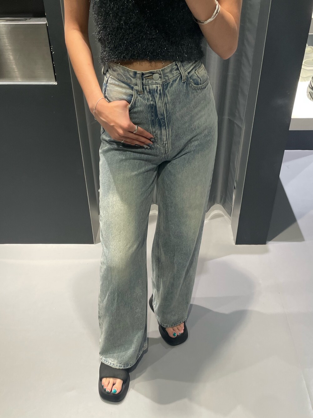 グレー系のタンクトップ、ブルー系のデニムパンツ、ブラック系のサンダルを着用したレディースの夏コーディネートの6枚目の写真