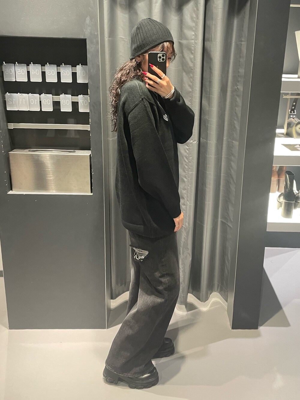 ブラック系のワンピース、ブラック系のデニムパンツ、ブラック系のブーツを着用したレディースの秋コーディネートの2枚目の写真