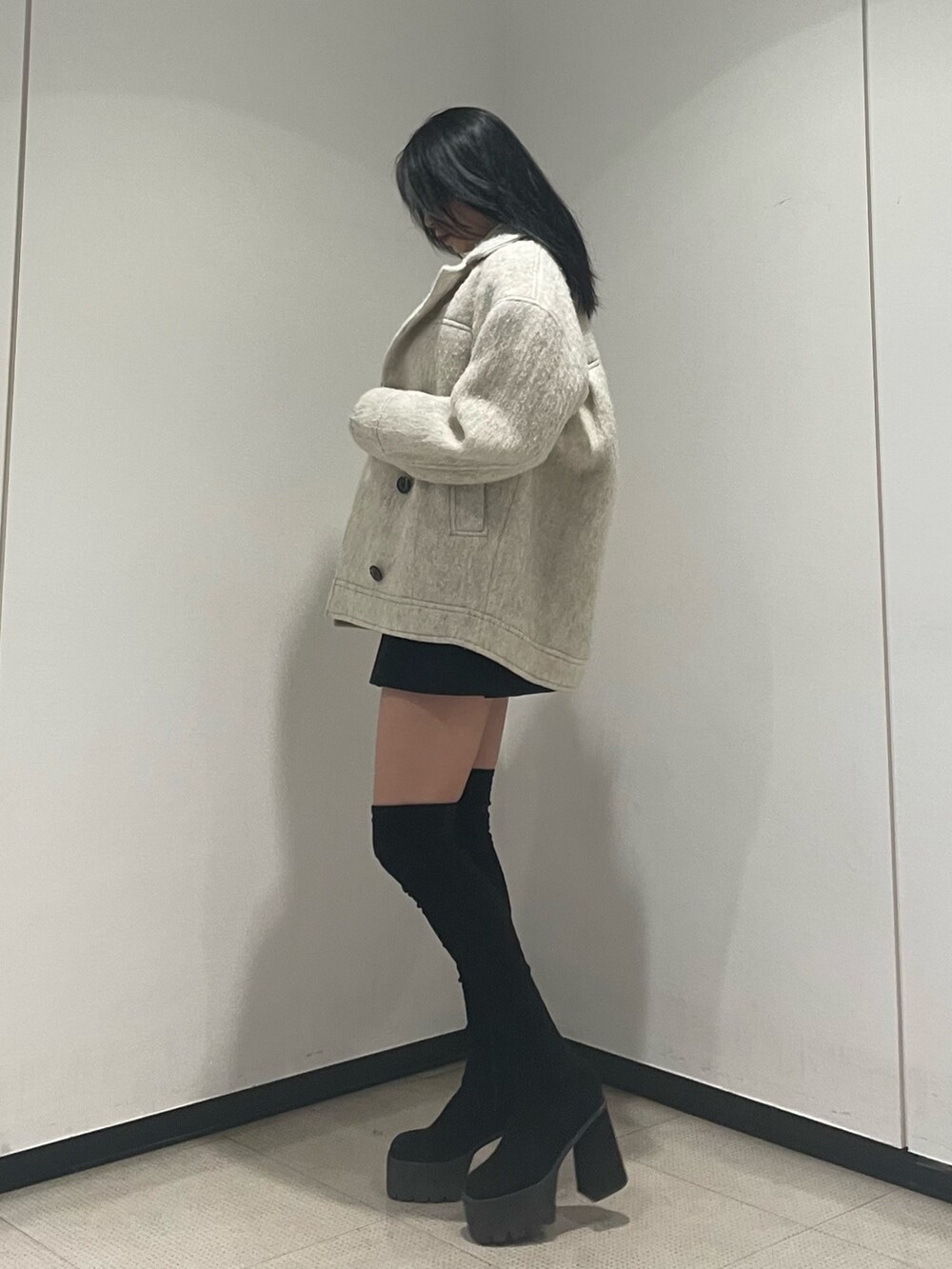 ホワイト系のニット/セーター、ホワイト系のピーコート、ブラック系のスカートを着用したレディースの冬コーディネートの2枚目の写真