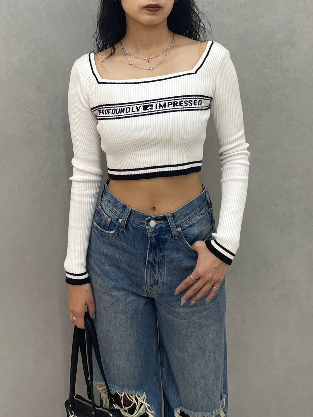 ホワイト系のニット/セーター、ブルー系のデニムパンツ、ブラック系のショルダーバッグを着用したレディースの夏コーディネートの4枚目の写真