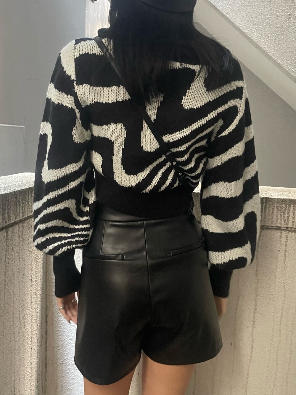 ブラック系のニット/セーター、ブラック系のその他パンツ、ブラック系のブーツを着用したレディースの冬コーディネートの6枚目の写真