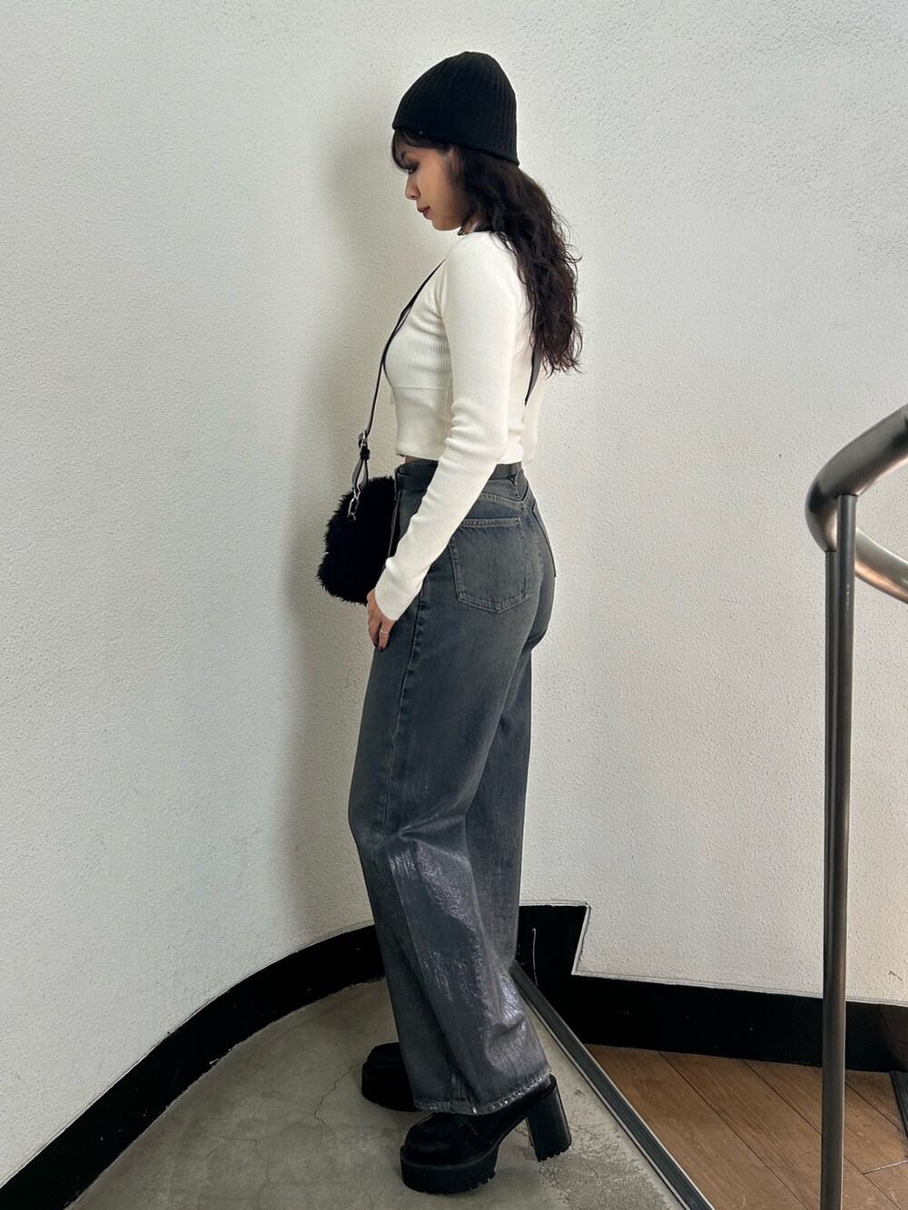 ホワイト系のニット/セーター、ブラック系のハンドバッグ、ブルー系のデニムパンツを着用したレディースの秋コーディネートの2枚目の写真