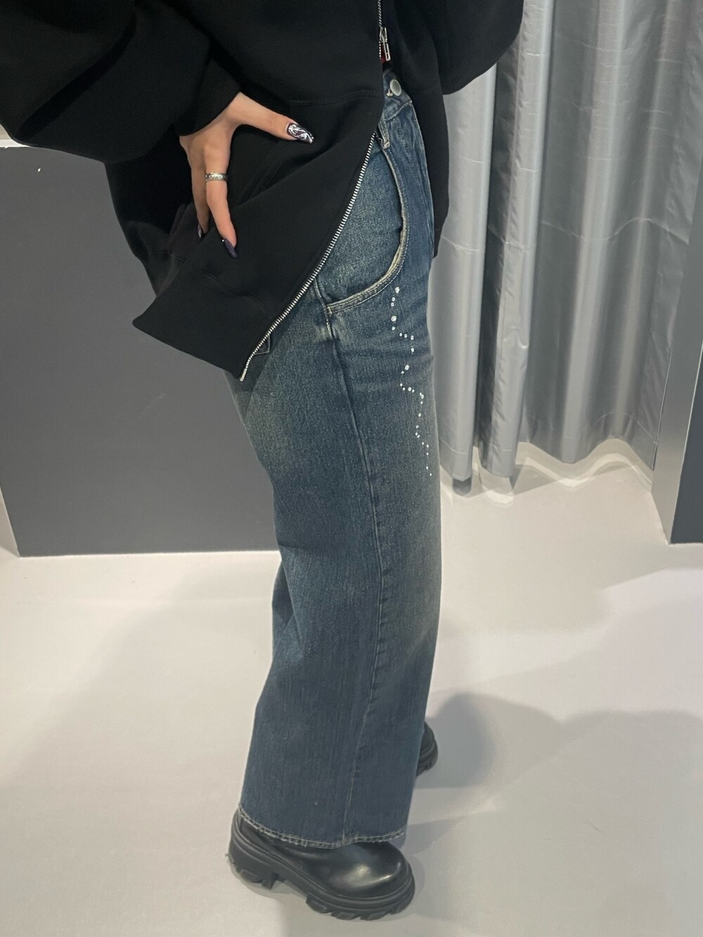 ブラック系のパーカー、ブルー系のデニムパンツ、ブラック系のブーツを着用したレディースの秋コーディネートの7枚目の写真