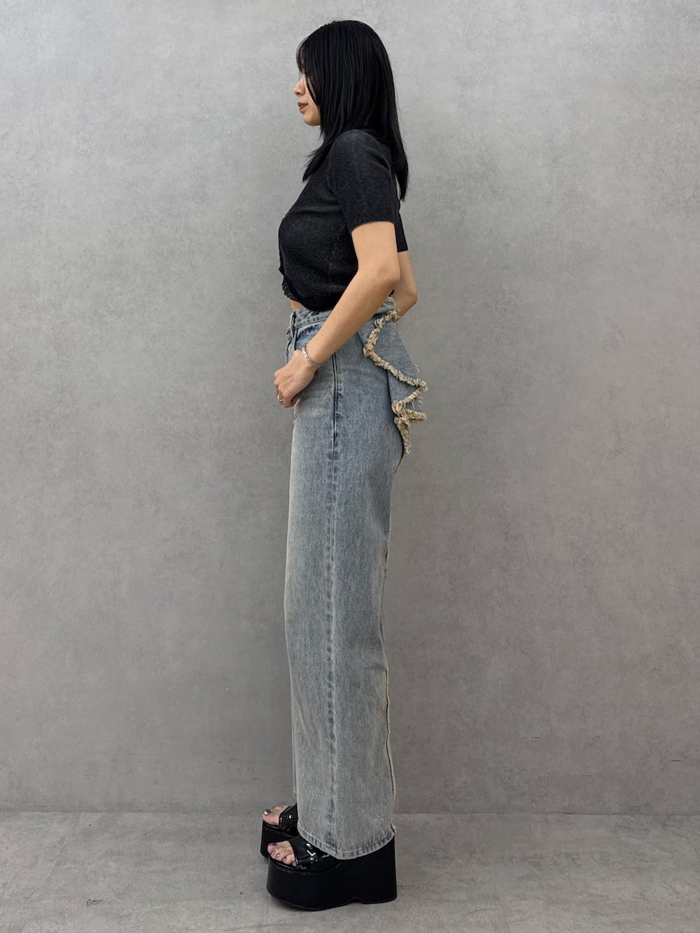 ブラック系のニット/セーター、ブルー系のデニムパンツ、ブラック系のサンダルを着用したレディースの春コーディネートの2枚目の写真