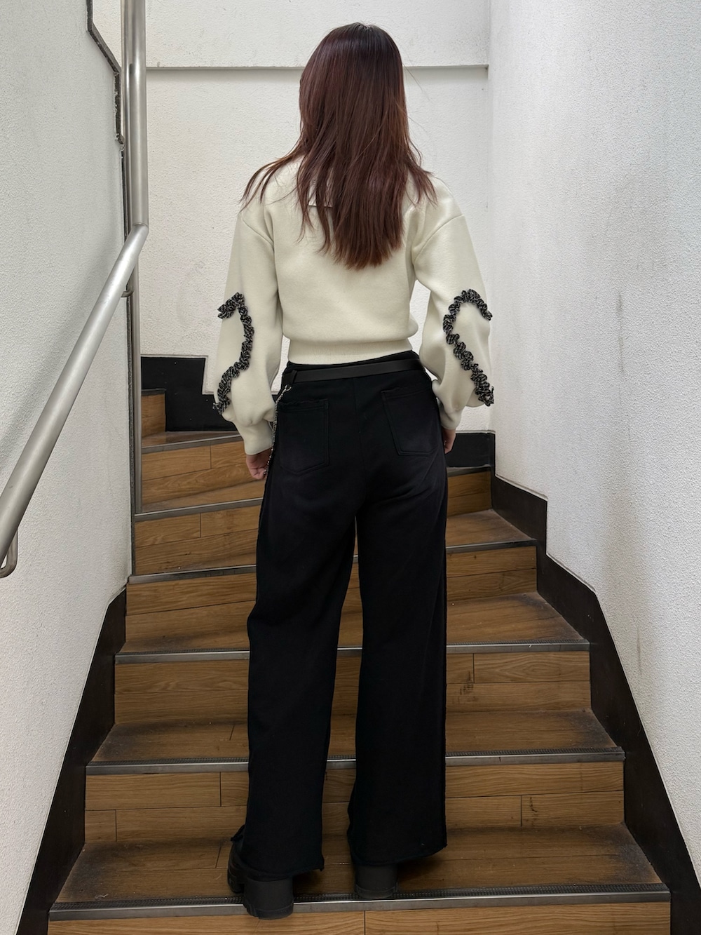 ホワイト系のニット/セーター、ブラック系のスウェットパンツ、ブラック系のブーツを着用したレディースの冬コーディネートの3枚目の写真