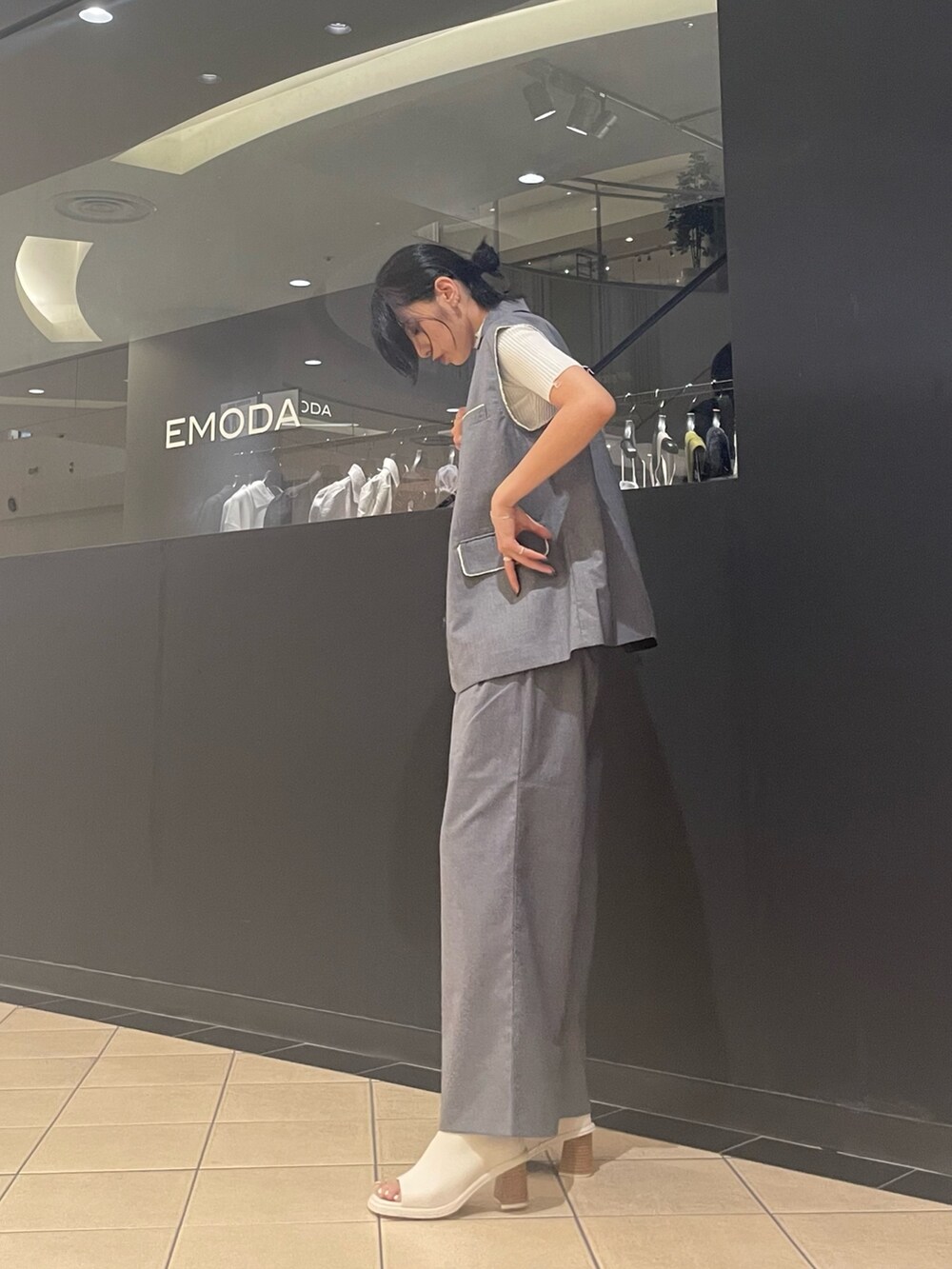 ホワイト系のニット/セーター、ホワイト系のハンドバッグ、グレー系のベストを着用したレディースの夏コーディネートの2枚目の写真