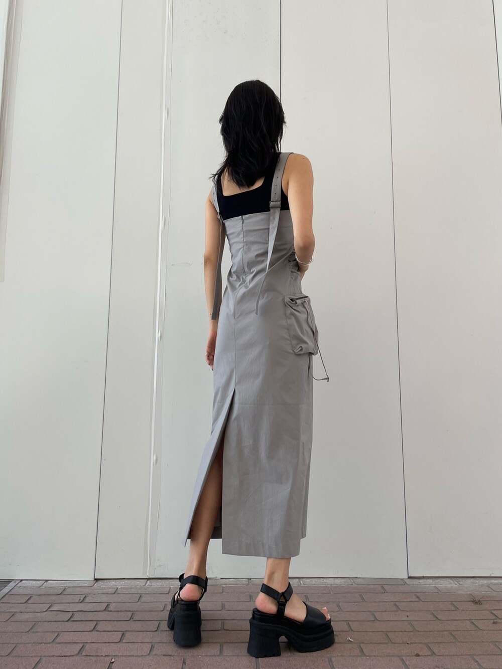 グレー系のワンピース、ブラック系のタンクトップ、ブラック系のサンダルを着用したレディースの夏コーディネートの3枚目の写真
