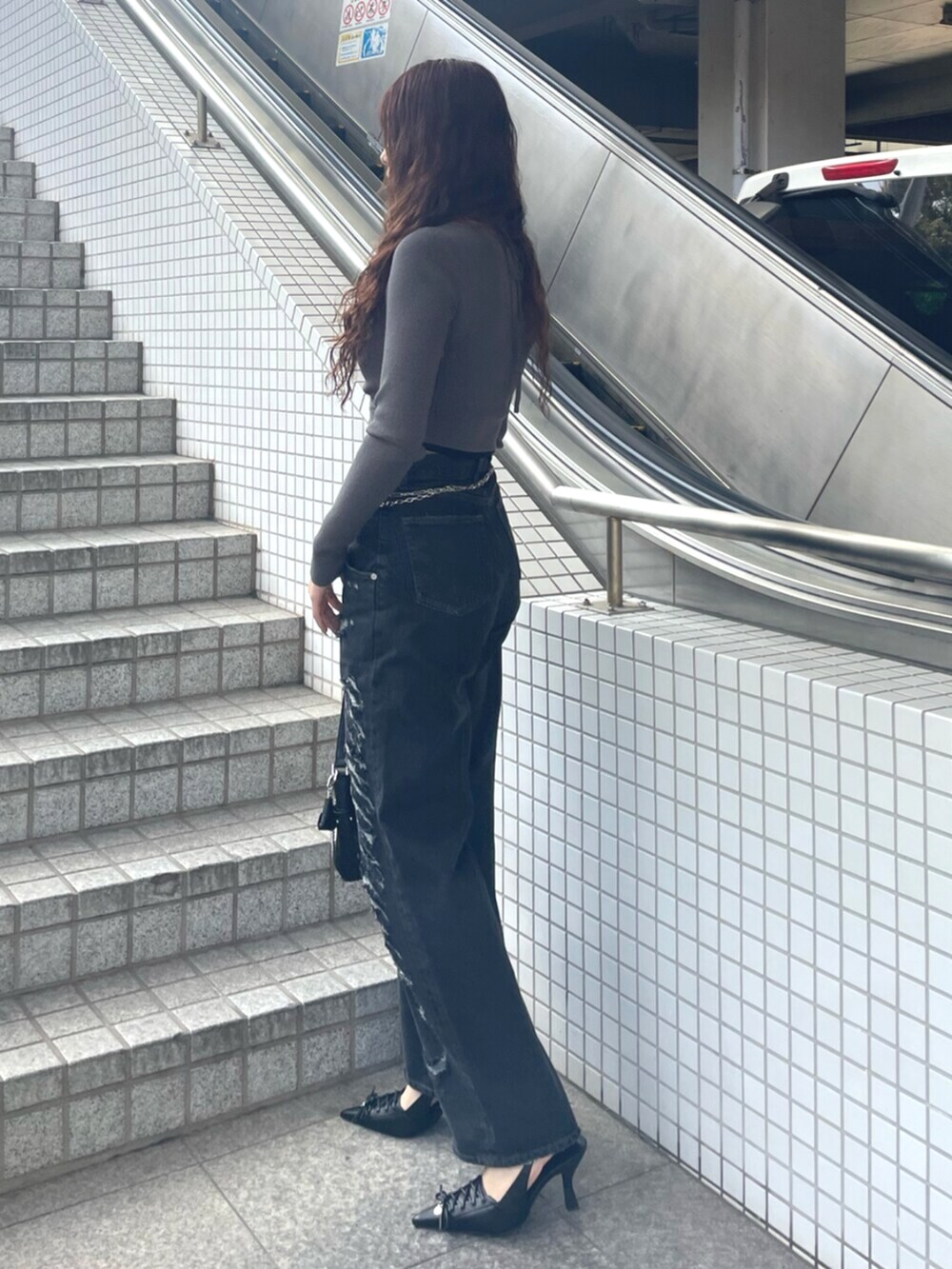 ブラック系のデニムパンツ、ブラック系のハンドバッグ、ブラック系のパンプスを着用したレディースの春コーディネートの2枚目の写真