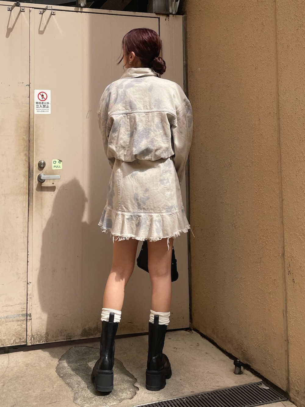 ホワイト系のデニムジャケット、ホワイト系のワンピース、ブラック系のハンドバッグを着用したレディースの春コーディネートの3枚目の写真