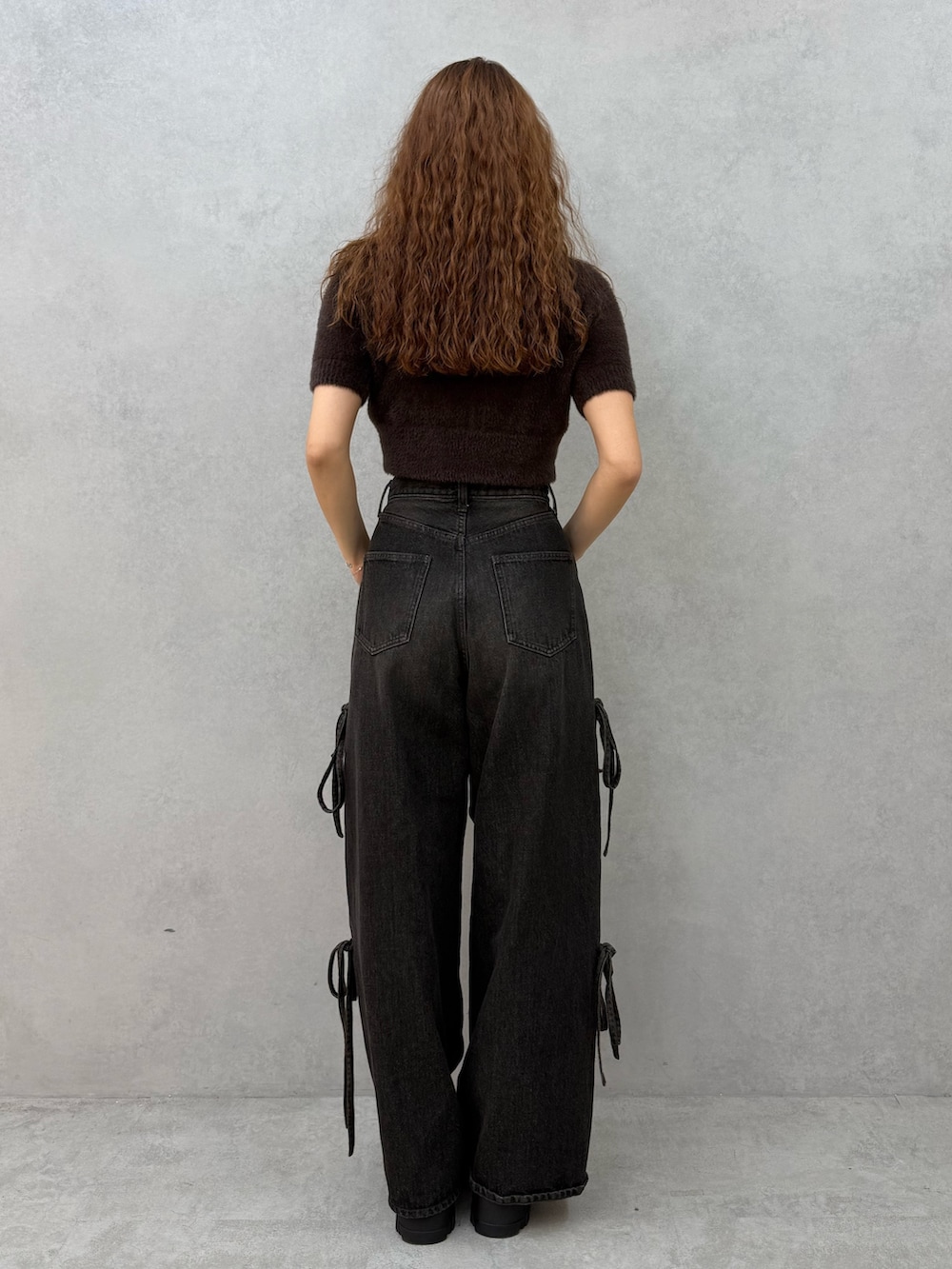 ブラウン系のニット/セーター、ブラック系のデニムパンツ、ブラウン系のブーツを着用したレディースの夏コーディネートの3枚目の写真