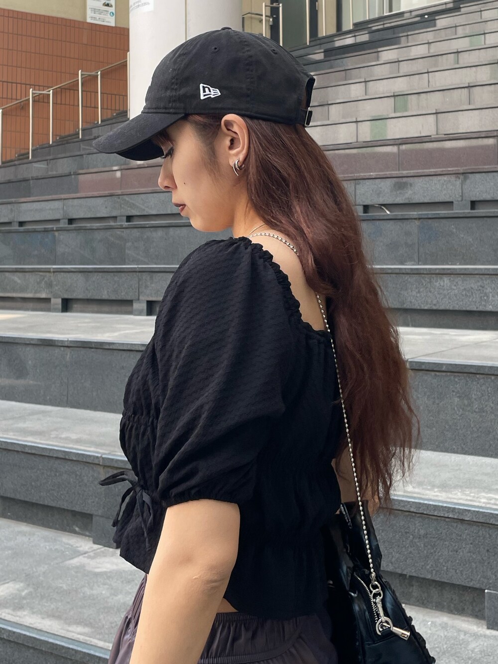 ブラック系のハンドバッグ、ブラック系のTシャツ/カットソー、ブラウン系のその他パンツを着用したレディースの春コーディネートの5枚目の写真