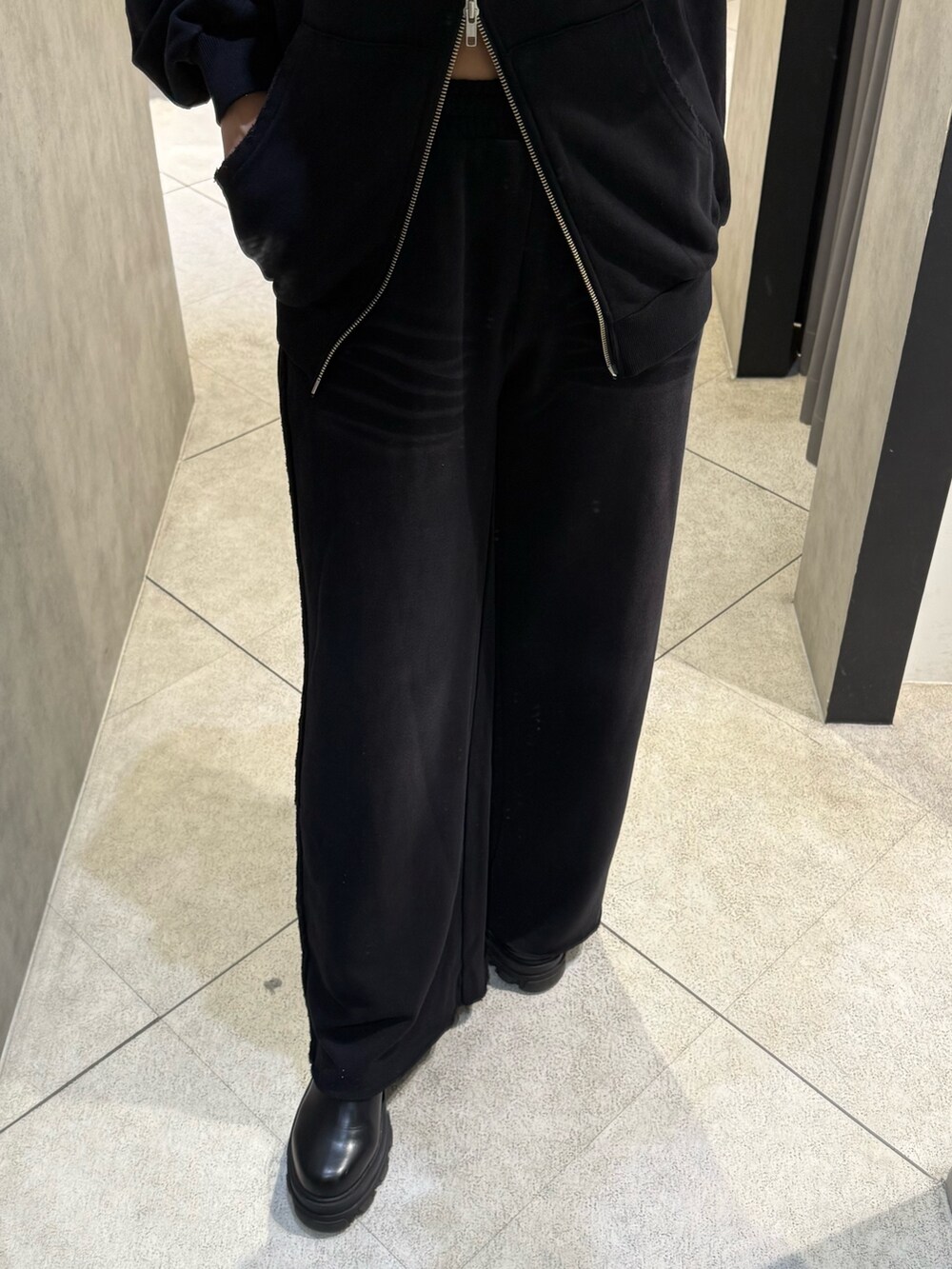 ブラック系のパーカー、ブラック系のスウェットパンツ、ブラック系のブーツを着用したレディースの秋コーディネートの6枚目の写真