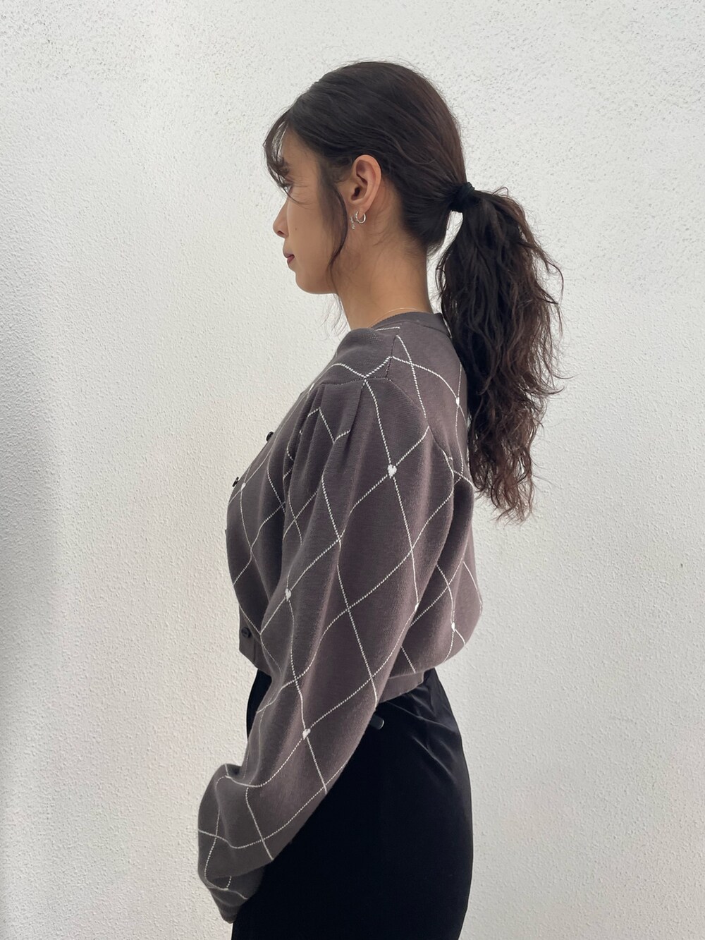 グレー系のニット/セーター、ブラック系のハンドバッグ、ブラック系のスカートを着用したレディースの秋コーディネートの5枚目の写真