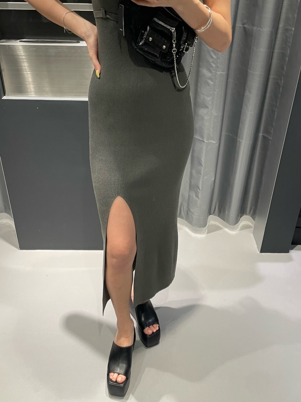 ブラック系のハンドバッグ、グレー系のワンピース、ブラック系のサンダルを着用したレディースの春コーディネートの5枚目の写真