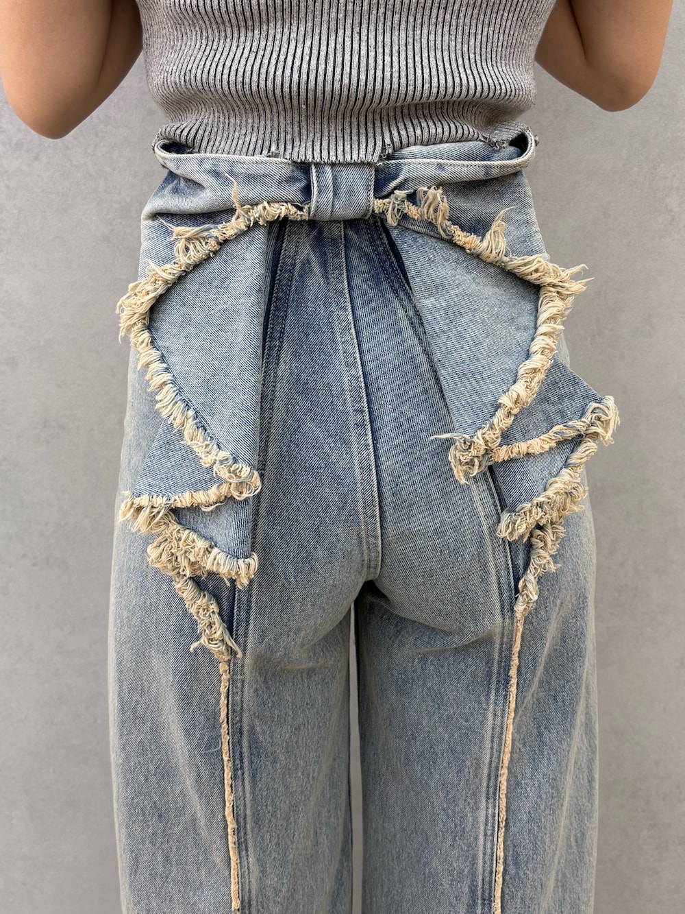 グレー系のニット/セーター、ブルー系のデニムパンツ、ブラック系のサンダルを着用したレディースの春コーディネートの7枚目の写真