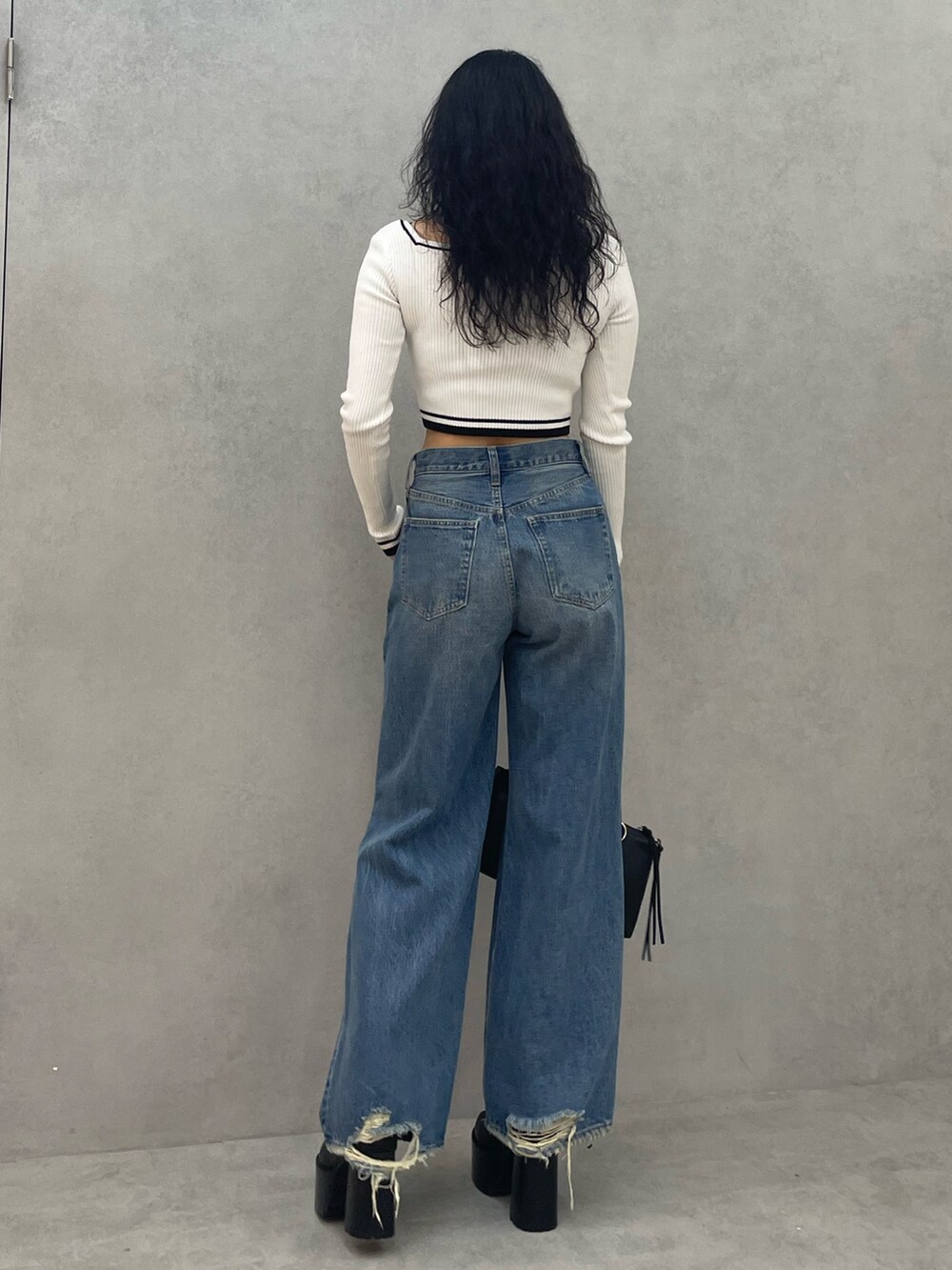 ホワイト系のニット/セーター、ブルー系のデニムパンツ、ブラック系のショルダーバッグを着用したレディースの夏コーディネートの3枚目の写真