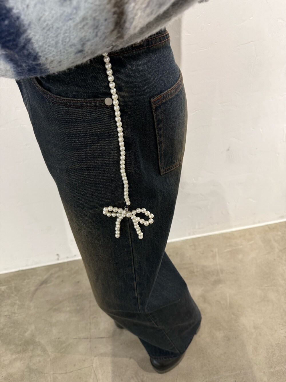 グレー系のニット/セーター、ブルー系のデニムパンツ、ブラック系のブーツを着用したレディースの秋コーディネートの5枚目の写真