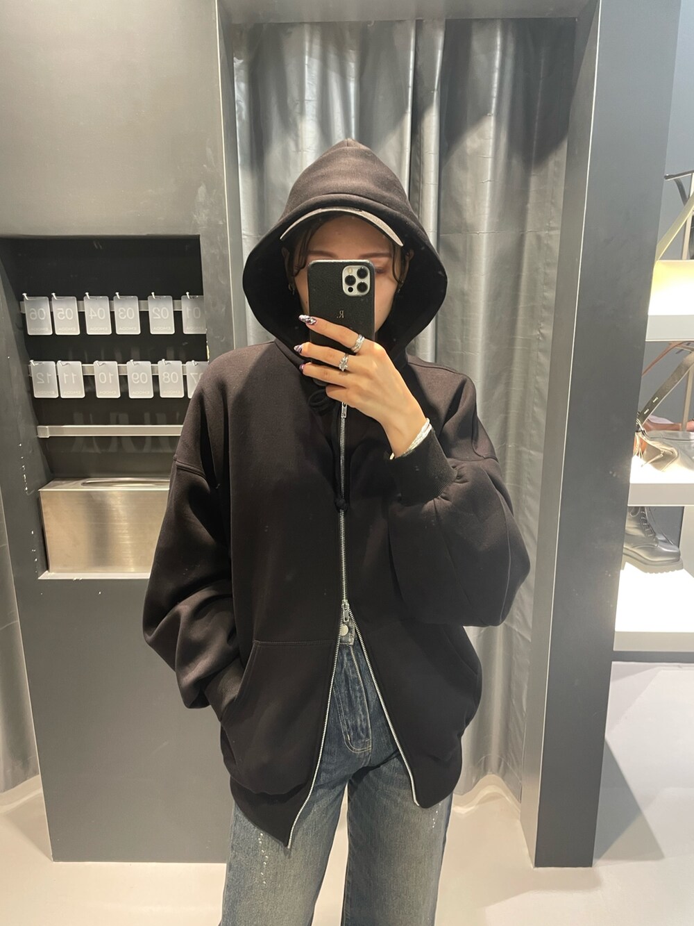 ブラック系のパーカー、ブルー系のデニムパンツ、ブラック系のブーツを着用したレディースの秋コーディネートの4枚目の写真