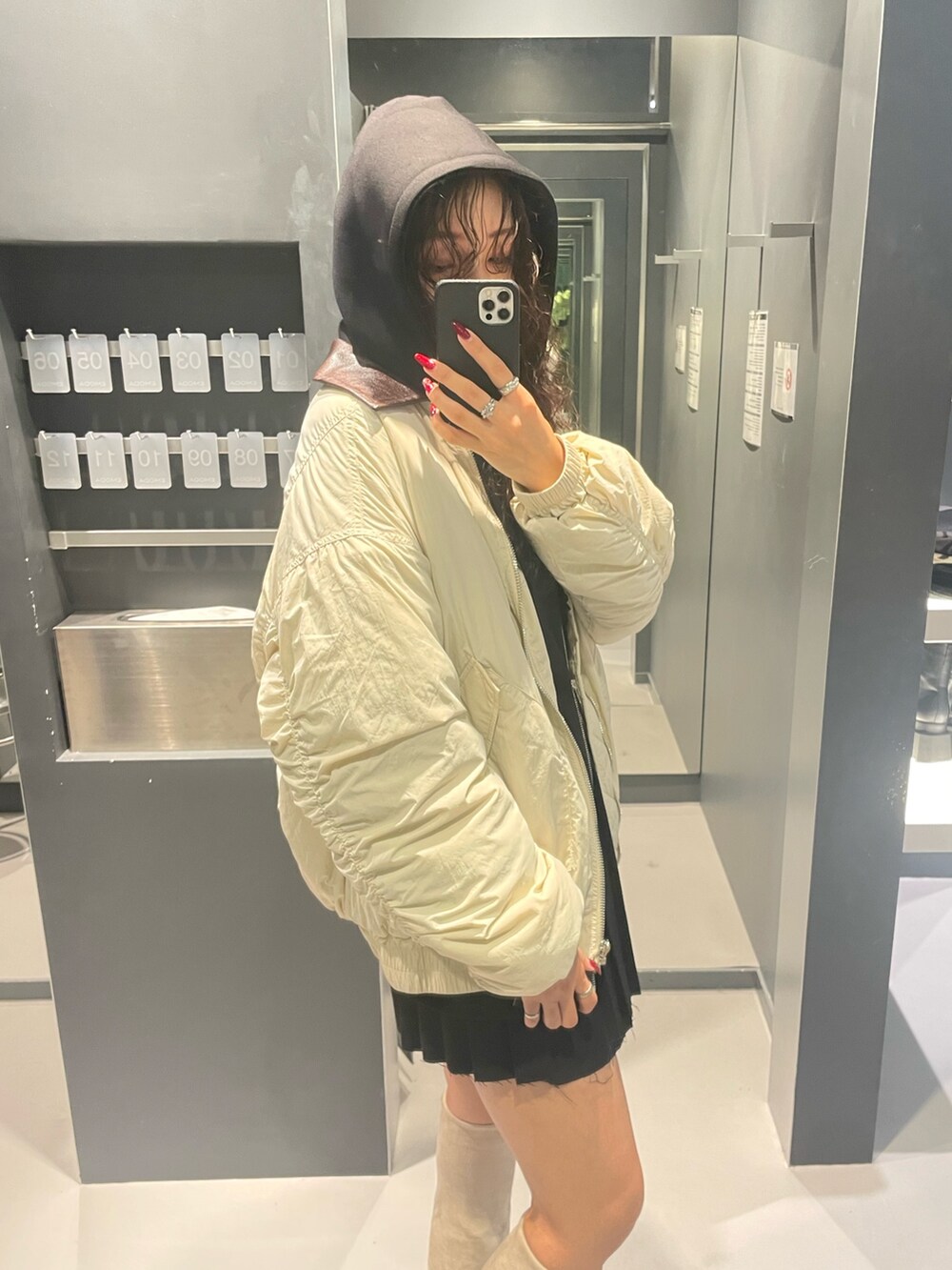 ブラック系のパーカー、ホワイト系のブルゾン、ブラック系のスカートを着用したレディースの秋コーディネートの5枚目の写真