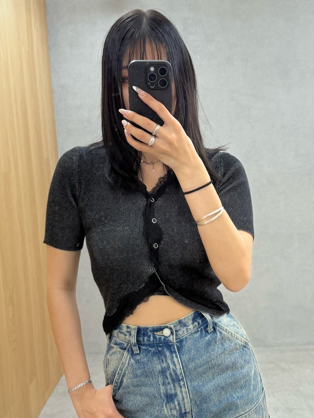 ブラック系のニット/セーター、ブルー系のデニムパンツ、ブラック系のサンダルを着用したレディースの春コーディネートの4枚目の写真