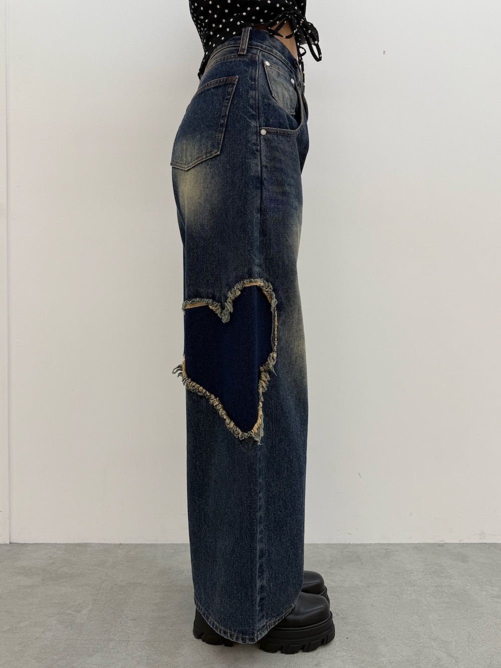レッド系のニット/セーター、ブルー系のデニムパンツ、ブラック系のブーツを着用したレディースの夏コーディネートの6枚目の写真