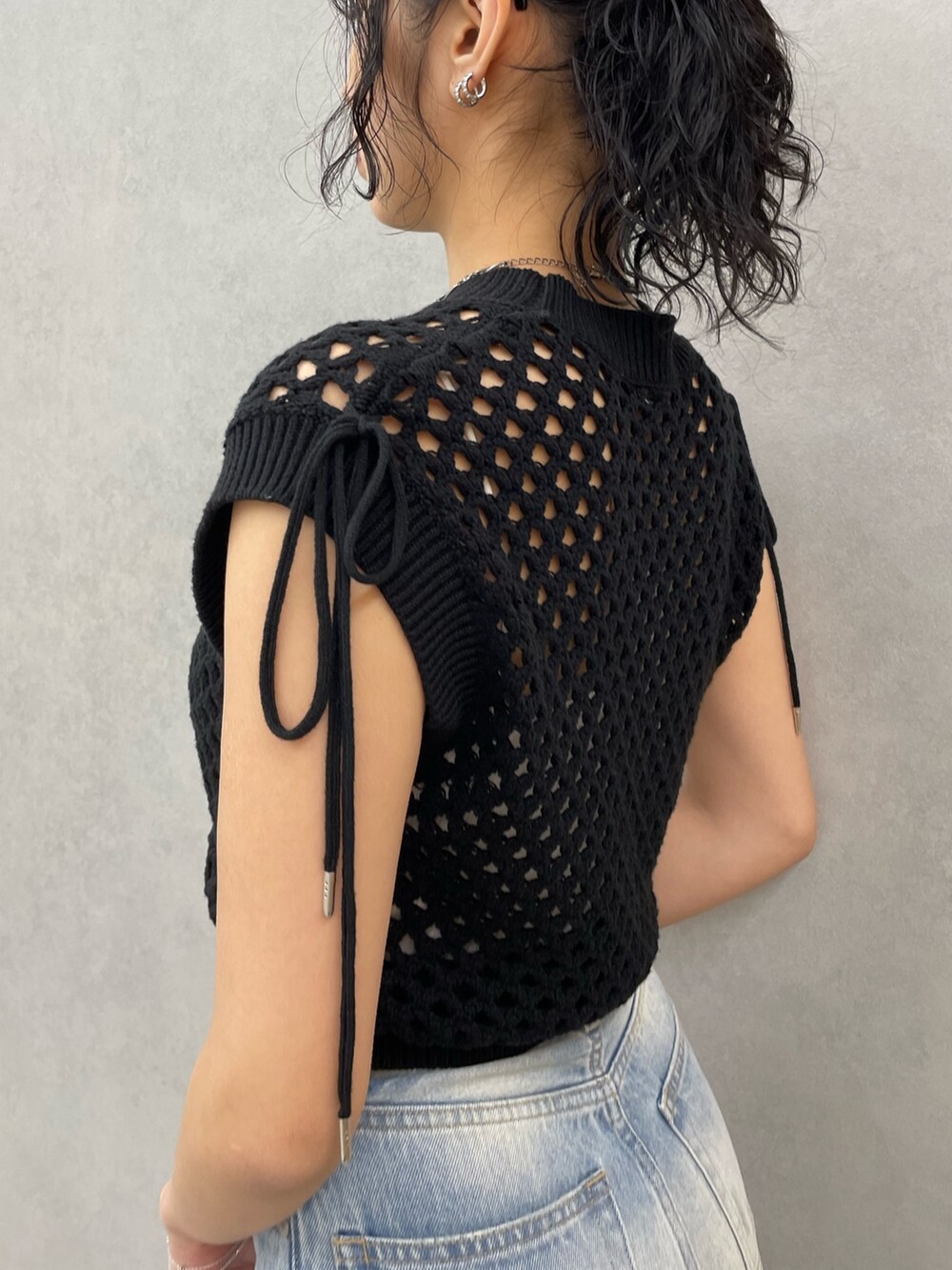 ブラック系のタンクトップ、ホワイト系のキャミソール、ブルー系のデニムパンツを着用したレディースの春コーディネートの5枚目の写真